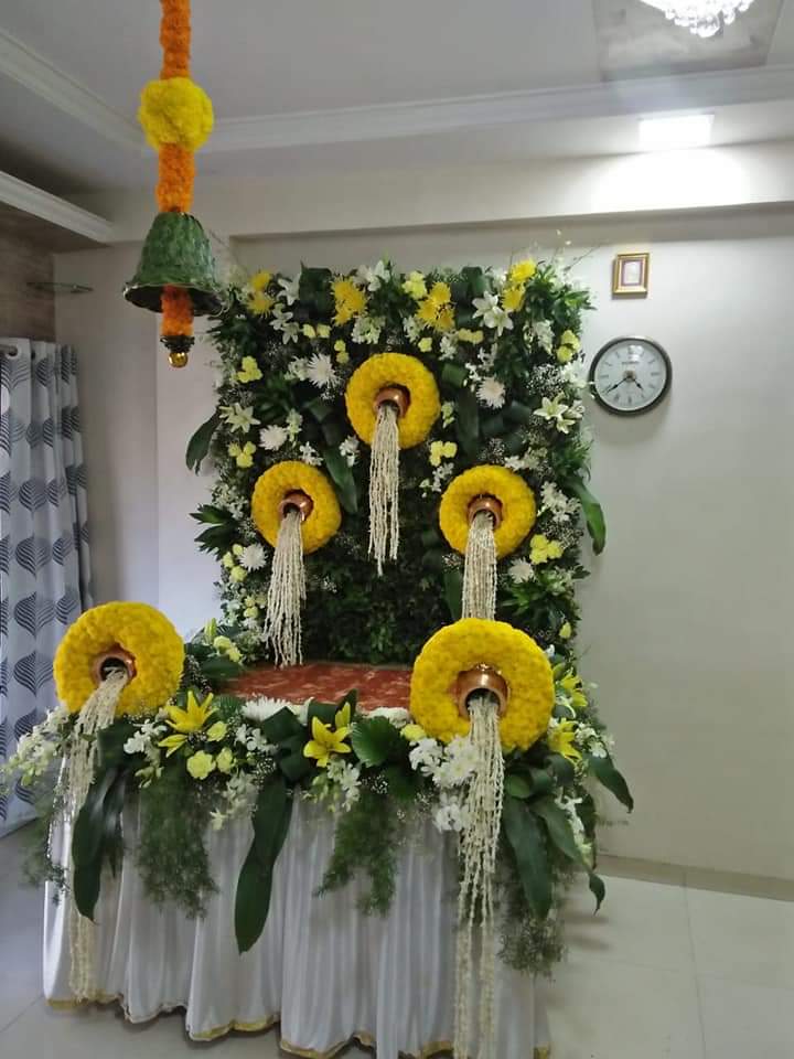 Ganpati flower decoration with yellow flowers, white strings, yellow lilies, white chrysanthemums, and green foliage for festive pooja setup.