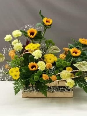 Sunflower floral arrangement in wooden planter with yellow flowers, carnations, green chrysanthemums and decorative foliage