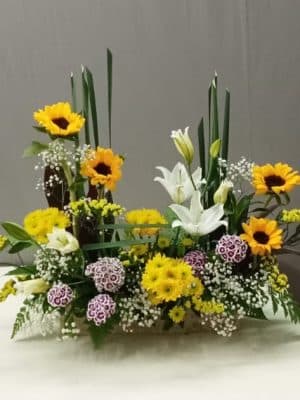 White Oriental lilies with sunflowers, typha grass, gypsophila, and statice in an elegant floral arrangement.