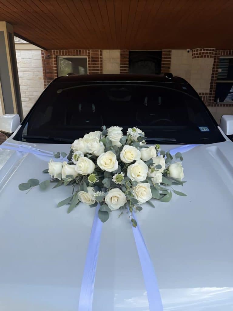 white car decoration featuring fresh white roses, eucalyptus leaves, and delicate fillers arranged on the bonnet for wedding and bridal entry in Mumbai.