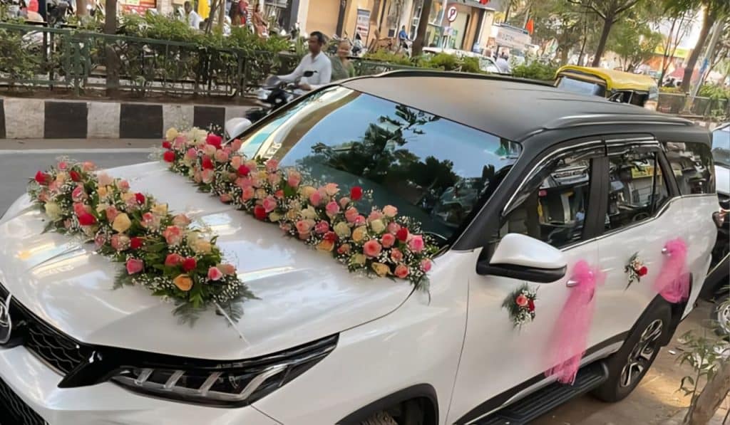 car decoration with fresh flowers Beautiful wedding car decoration with pink roses, red roses, peach roses, white flowers, and baby’s breath arranged on the bonnet and side doors of a white luxury car.