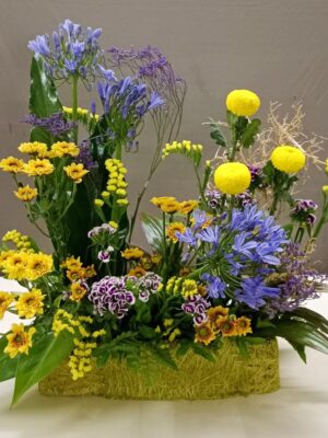 Premium floral arrangement with purple agapanthus, yellow chrysanthemums, statice, and seasonal fillers in decorative base