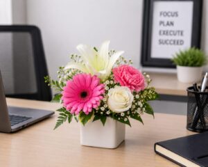 Office desk flower arrangement with pink gerbera, white lily, white rose, and carnation in a ceramic vase