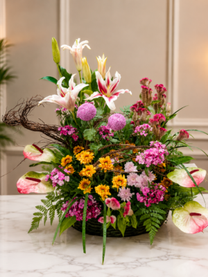 Colorful floral basket arrangement with white oriental lilies, pink anthuriums, yellow chrysanthemums, globe flowers, and seasonal fillers