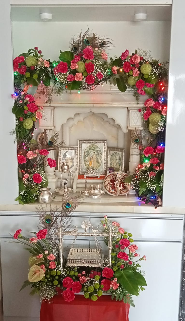 Beautiful Janmashtami home temple decoration with fresh flowers, a Krishna Jhula, peacock feathers, and floral garlands by FlowerFeathers Mumbai.