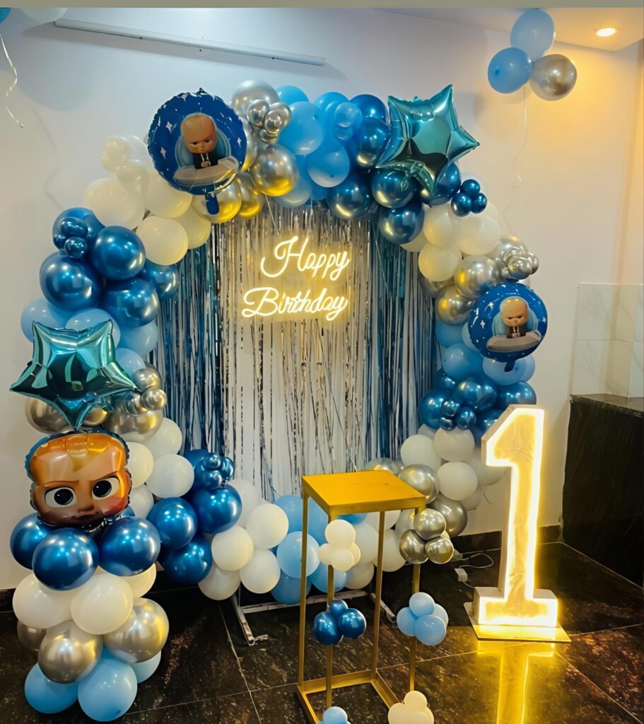 Boss Baby themed first birthday decoration with blue, white and silver balloon arch