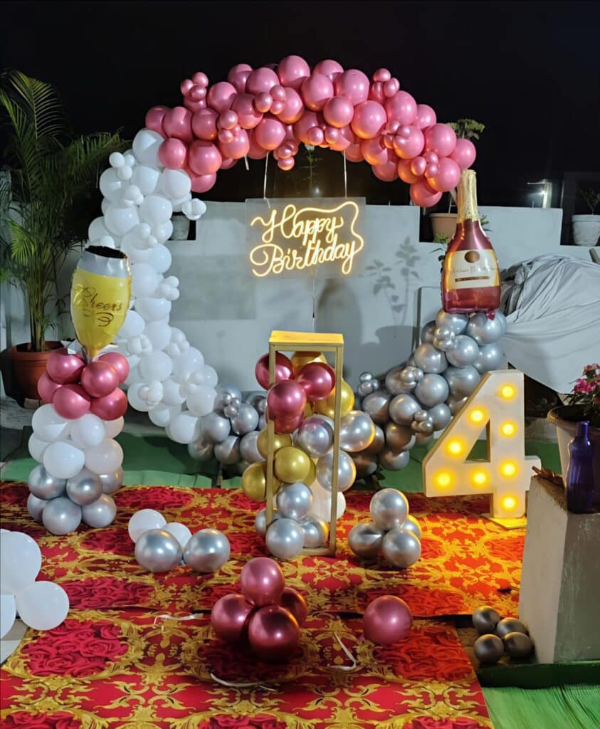 Happy Birthday decoration with a pink, white and silver balloon arch, a neon sign and the birthday number 4