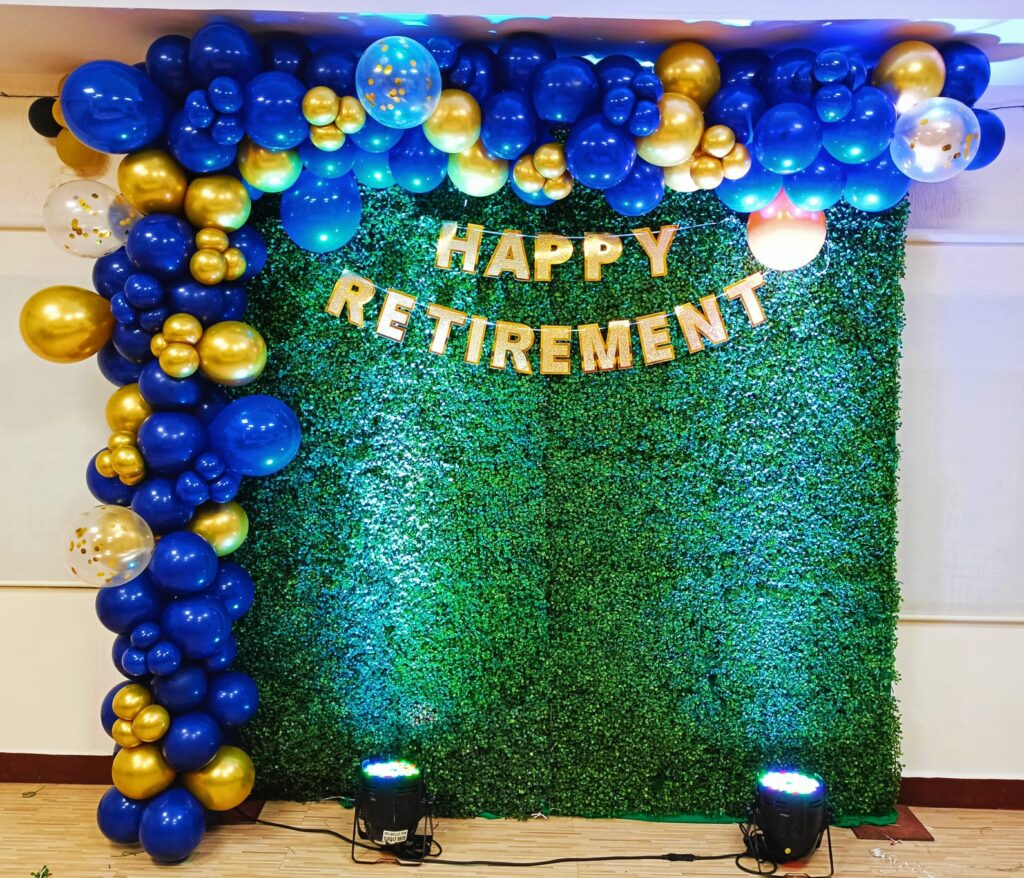 Happy Retirement balloon decoration with blue and gold balloons and a green backdrop