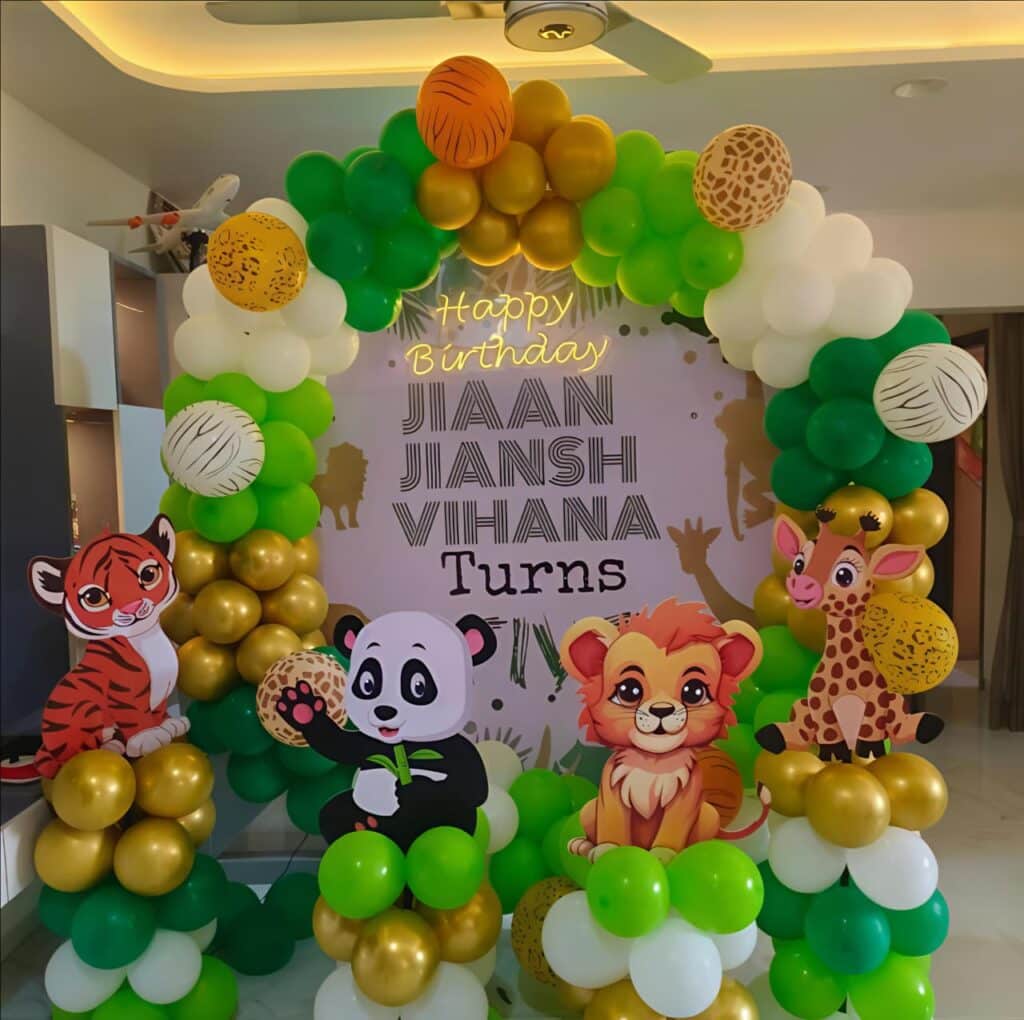 Jungle safari birthday decoration with green, gold and white balloon arch and animal cutouts
