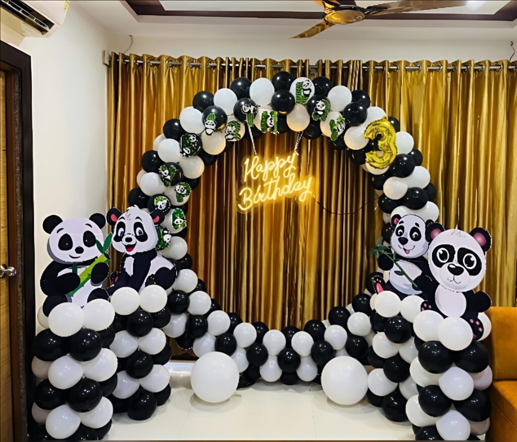 Panda-themed birthday decoration with black and white balloon arch and panda cutouts