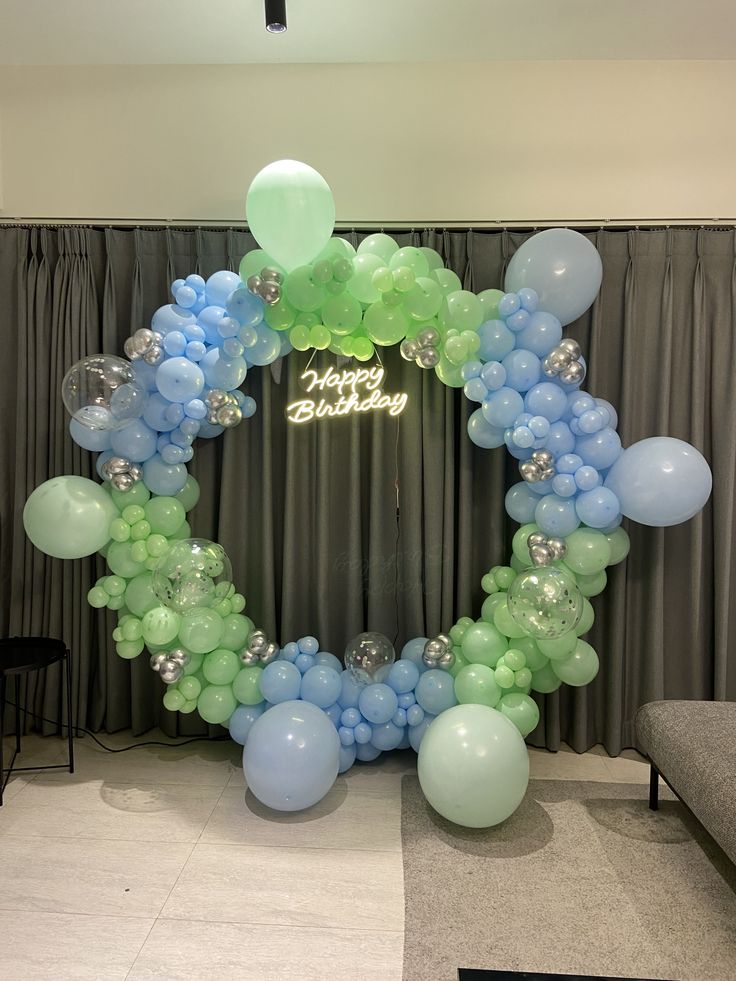 Pastel blue and green birthday balloon arch with silver balloons and a 'Happy Birthday' sign